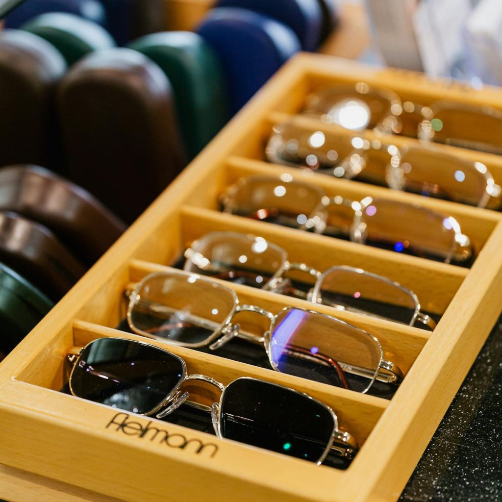 A collection of eyeglasses neatly arranged in a wooden tray at an eyewear store.